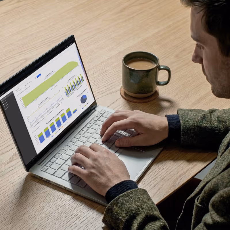Overshoulder photo of a person at a laptop, looking at a screenshot with graphs and charts from Invenda Atlas advertising application