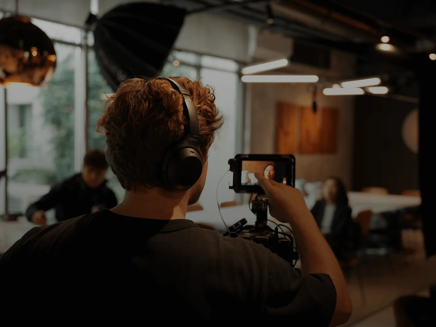 Une personne portant un casque enregistre une interview avec une caméra dans un intérieur moderne.