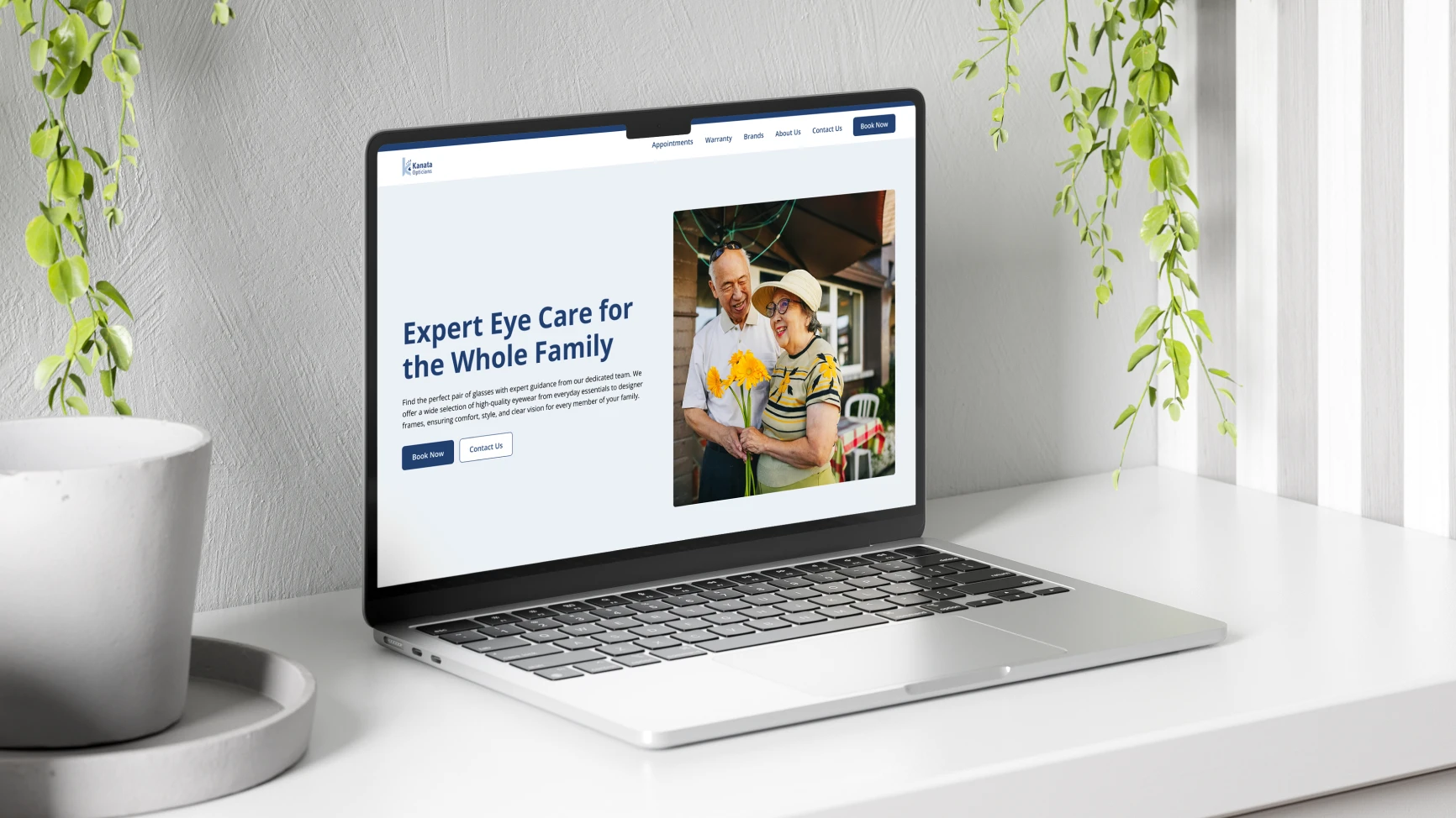 Laptop on white desk displaying a website for expert eye care featuring an elderly couple holding flowers and smiling.