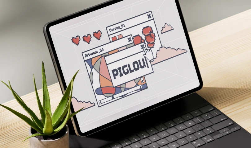 Tablet with keyboard on wooden table displaying pixel art windows with hearts, abstract shapes, and a gamertag reading PIGLOU.