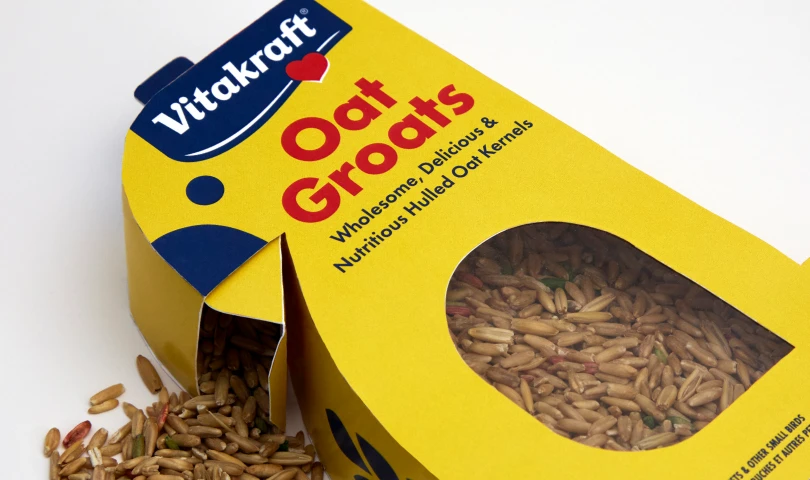 Yellow Vitakraft Oat Groats box with spilled hulled oat kernels visible around the box.
