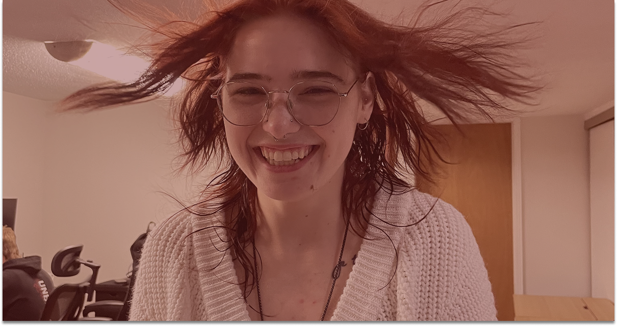 Amélia with red hair spread out, wearing glasses and a cream knit sweater, indoors with a red overlay