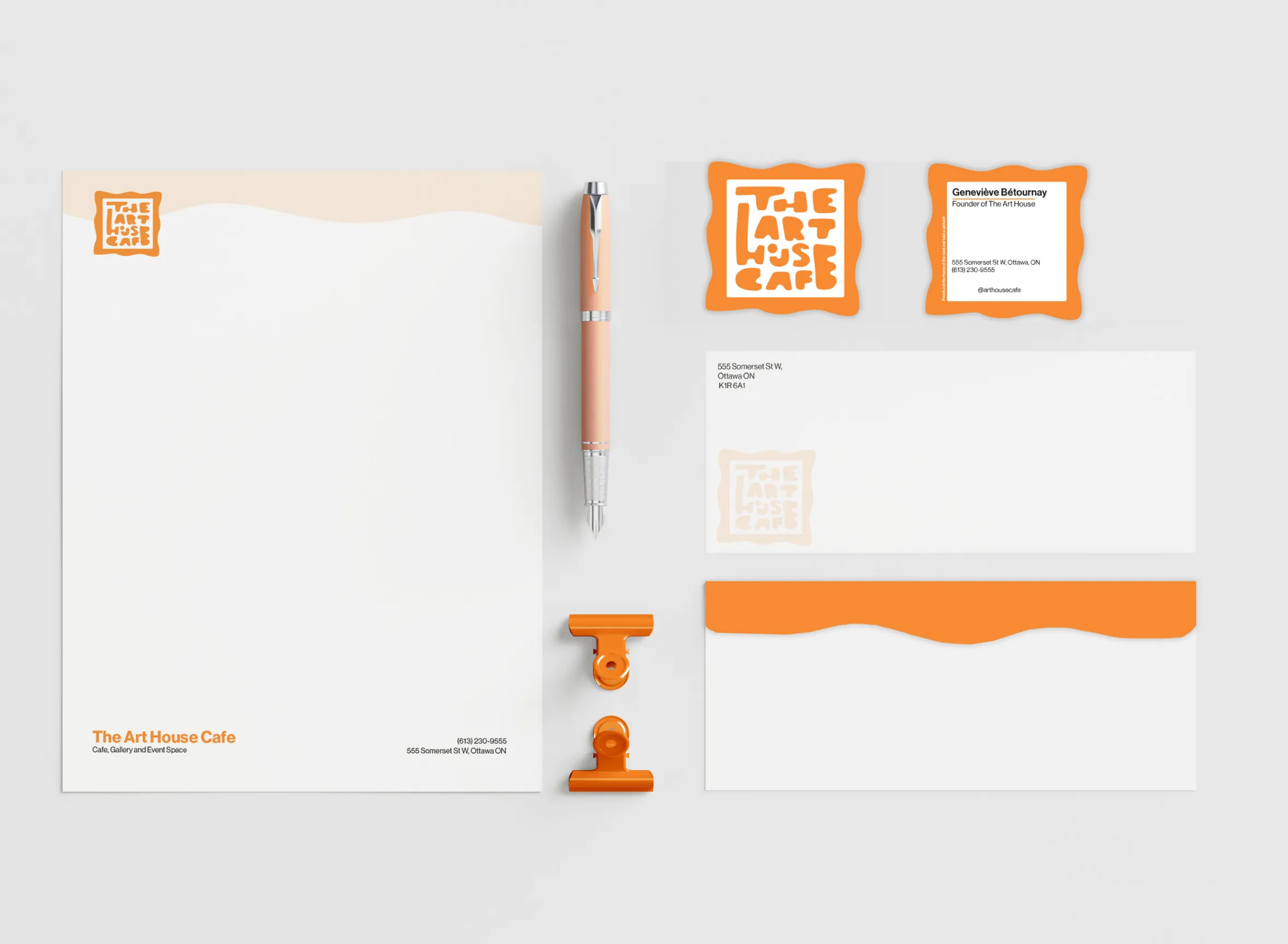 Branded stationery set for The Art House Cafe, including letterhead, pen, business cards, envelopes, and orange clips on a light background.