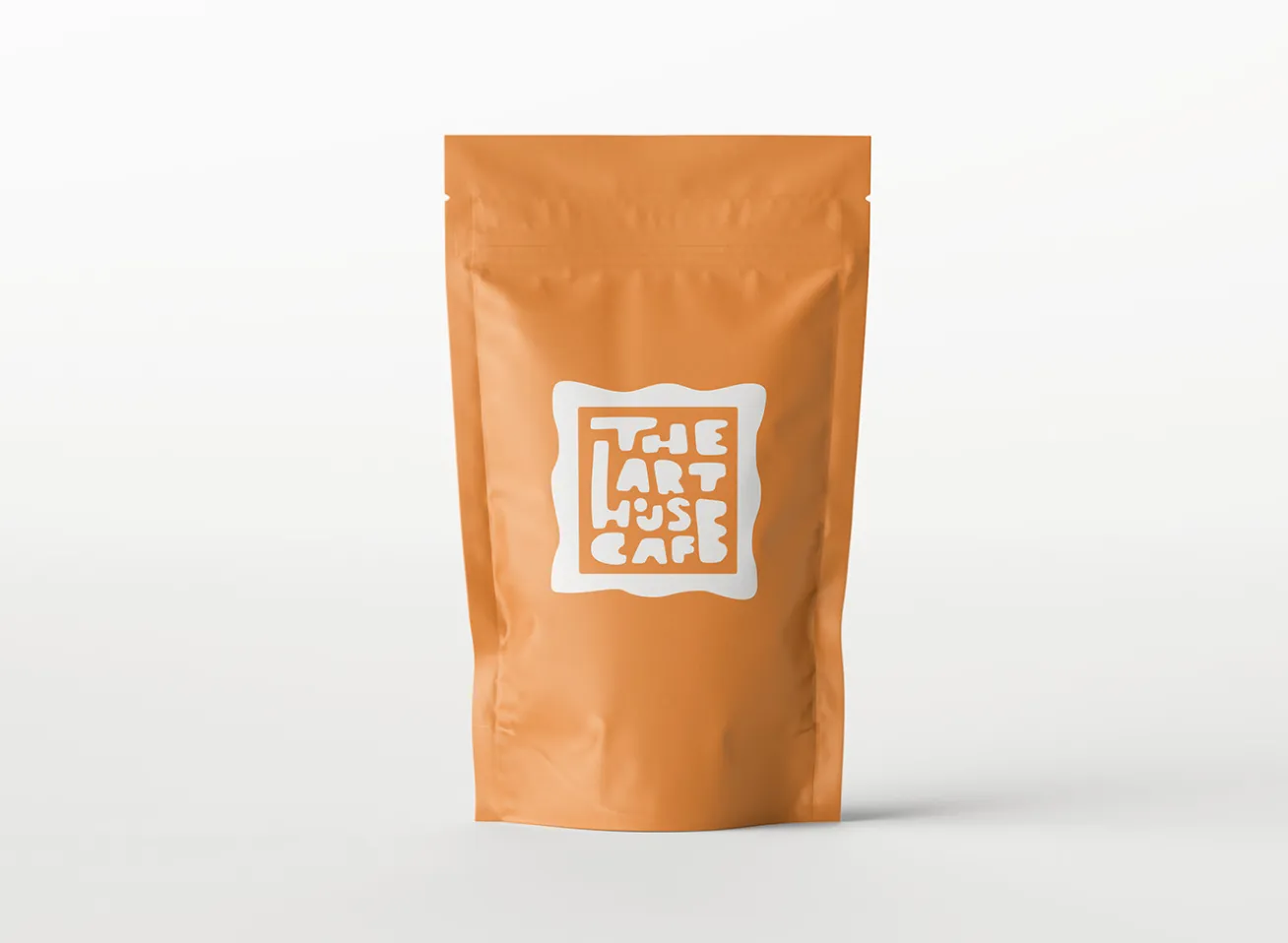Orange stand-up pouch with white logo reading 'The Art House Café' in stylized block letters.