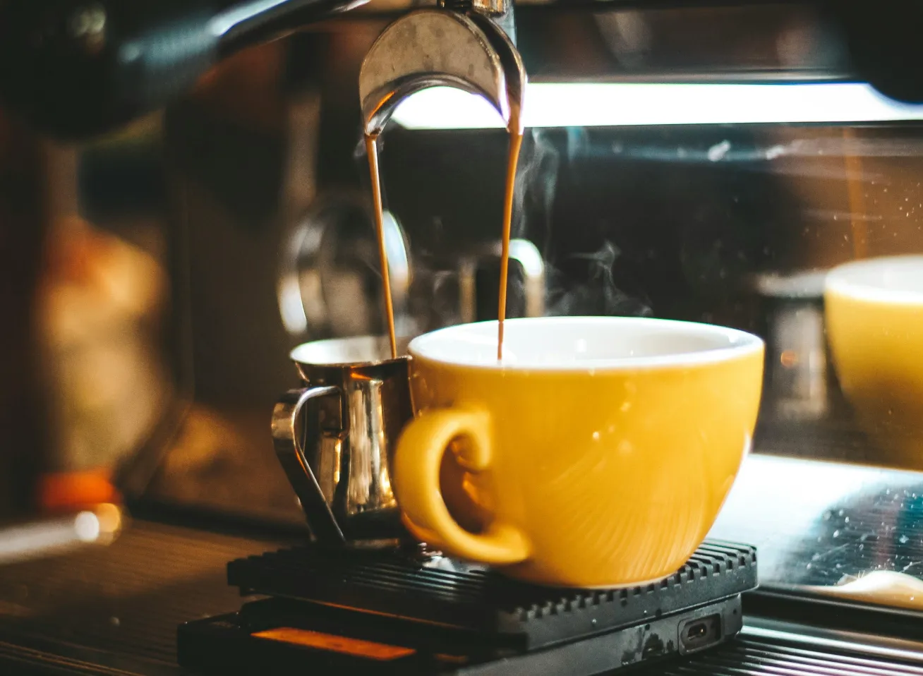 orange cup with coffee flowing into it