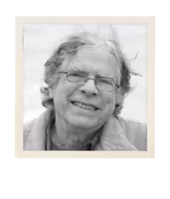 Black and white photo of an older man with glasses smiling softly.
