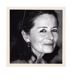 Black and white close-up portrait of a middle-aged woman smiling gently, with dark hair pushed back and wearing earrings.
