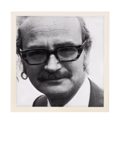 Black and white portrait of a man with glasses, mustache, and earring wearing a suit.