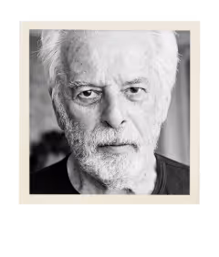 Black and white close-up portrait of an elderly man with white hair and beard looking directly at the camera.