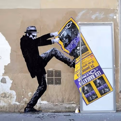 Muurschildering van een man met hoed en masker die een deur opent door een groot geel-paarse poster weg te trappen.