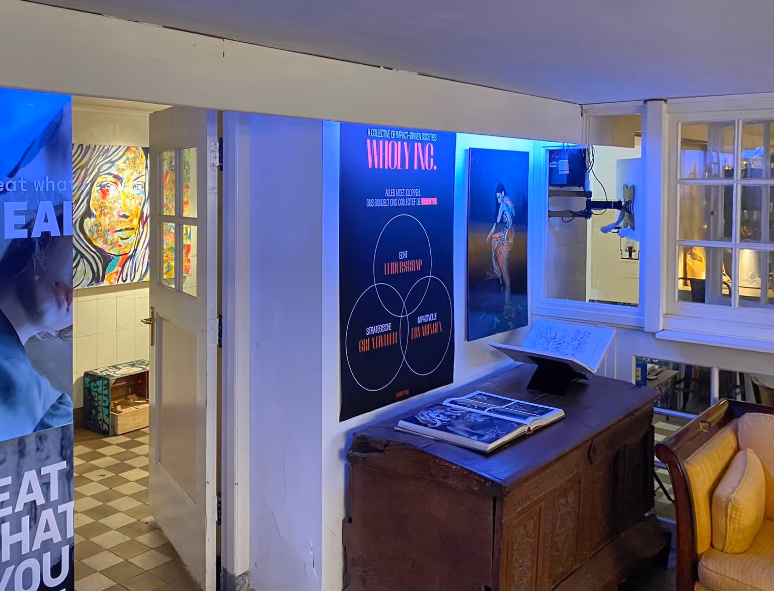 Galerij met schilderijen en een tafel met opengeslagen boeken, verlicht door blauw licht.