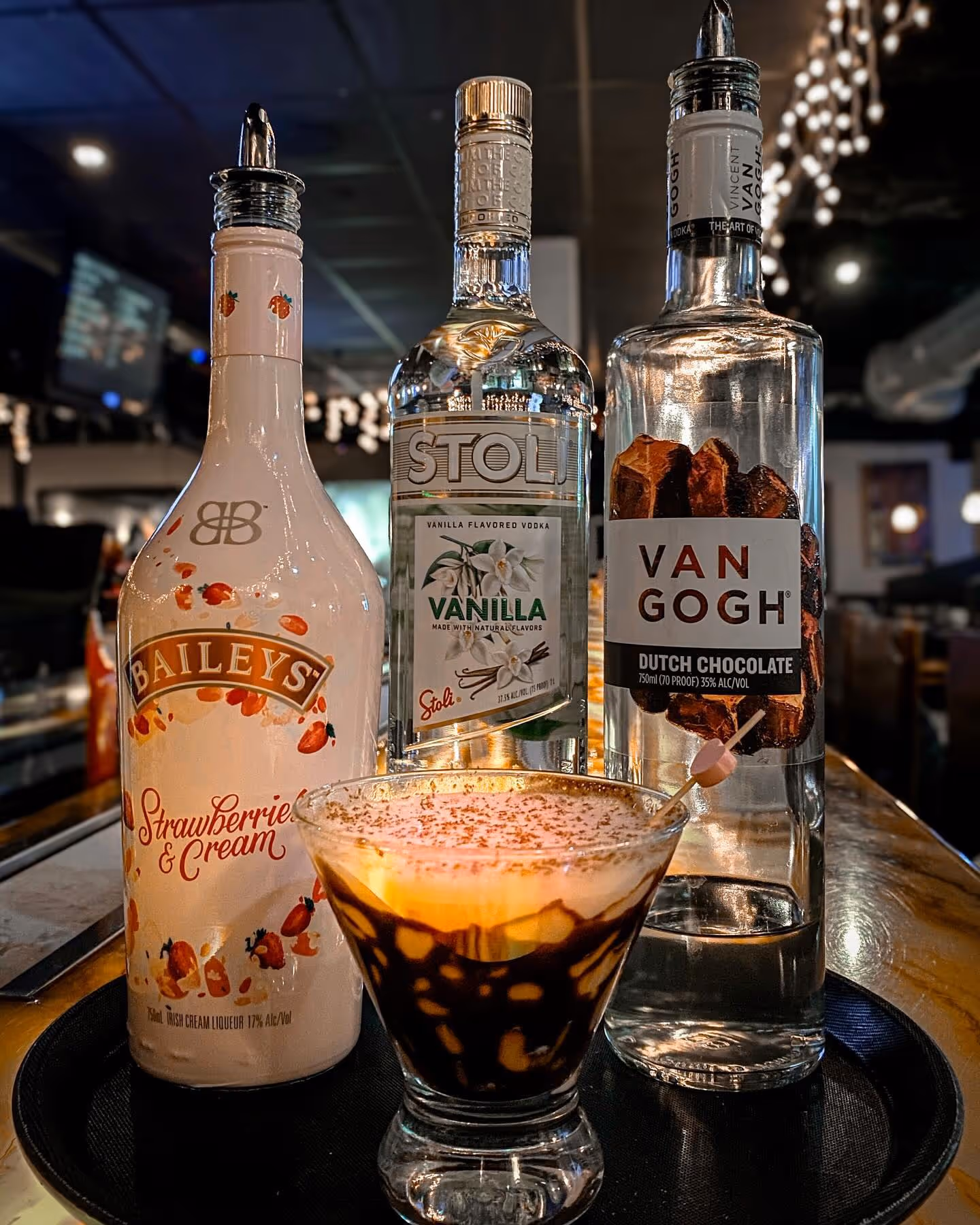 A Chocolate Covered Strawberry Martini with liquor bottles behind.
