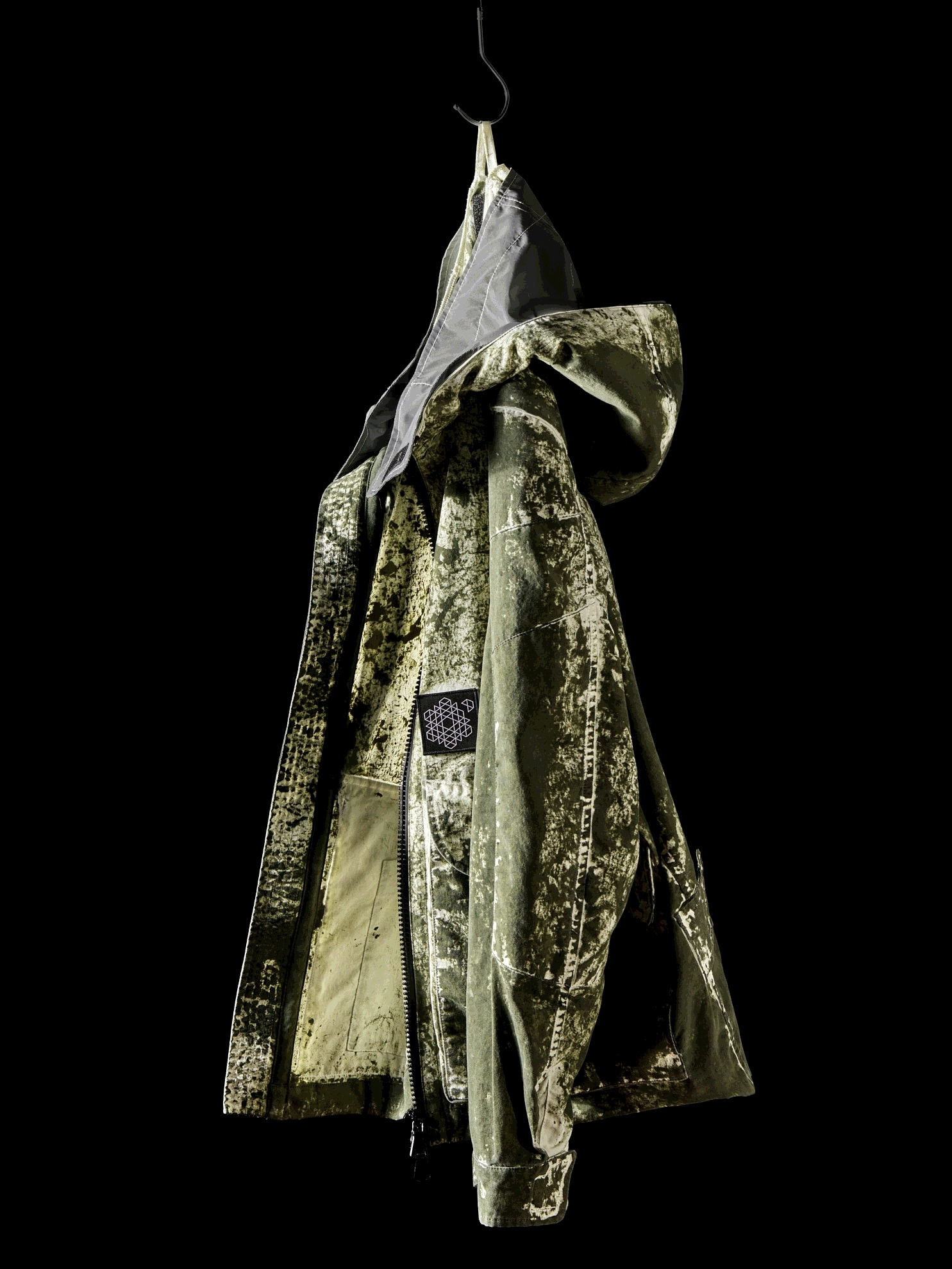 The garment carries what a production relationship produced. It cannot carry the relationship itself. Image Credit: Plurimus NO_S24_MK Hooded Jacket, Disrupt Green, 2024. 100% nylon, Disrupt garment-dye treatment; edition of 99 numbered pieces.