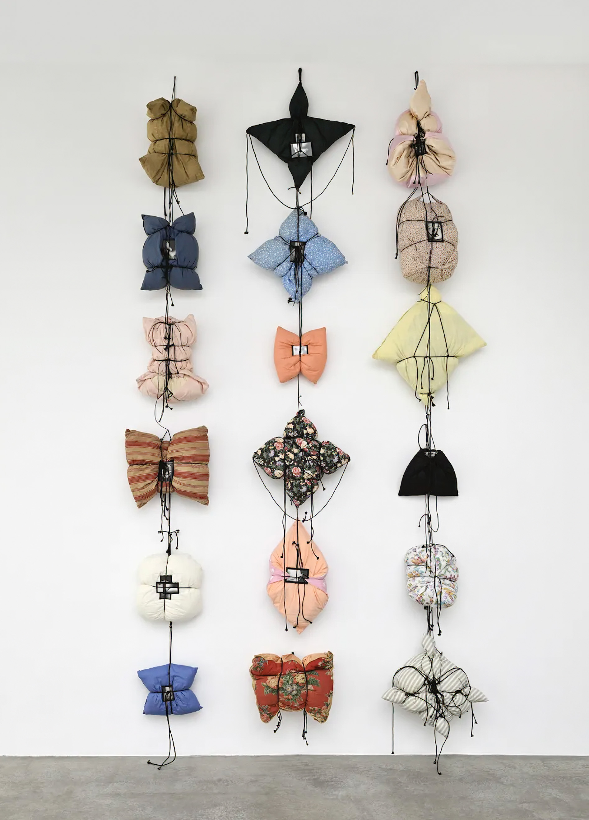 The cord compresses each pillow into a new figure, holding the photograph where the pressure is greatest. Image Credit: Annette Messager, Histoire des oreillers III, 1995–2026. Photo: Rebecca Fanuele.