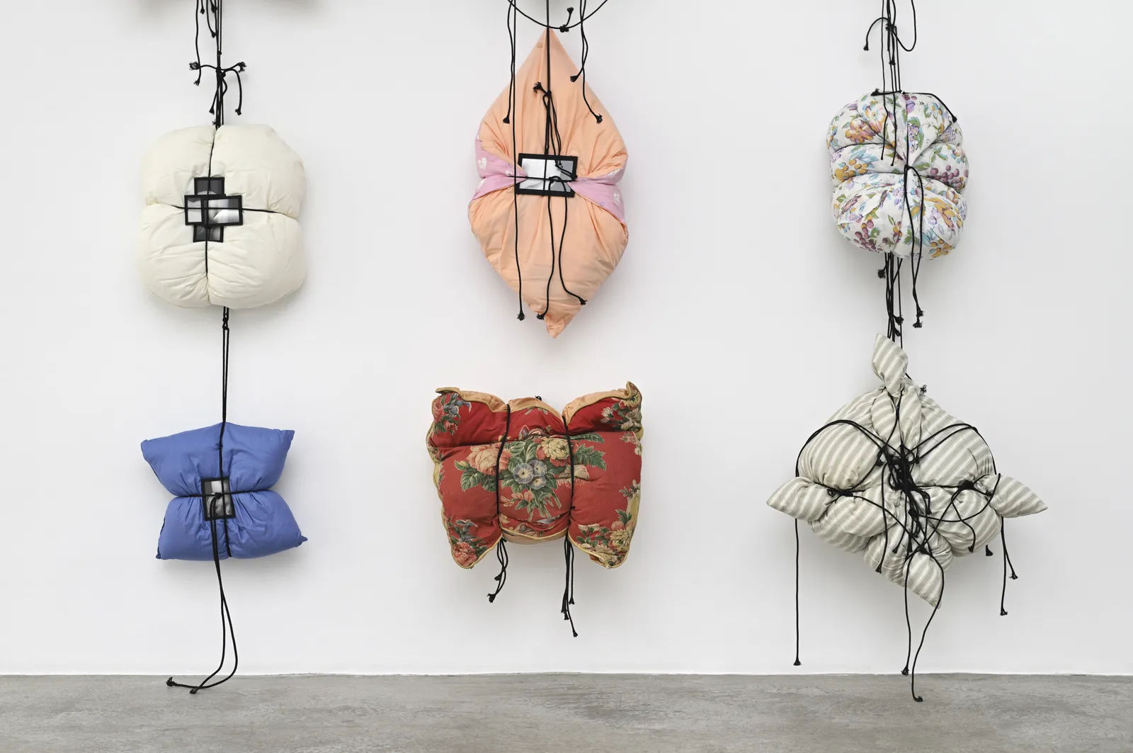 Cord presses the pillow into shape, with a fragment of the body fastened directly over the point of pressure. Image Credit: Annette Messager, Histoire des oreillers III (detail), 1995–2026. Photo: Rebecca Fanuele.