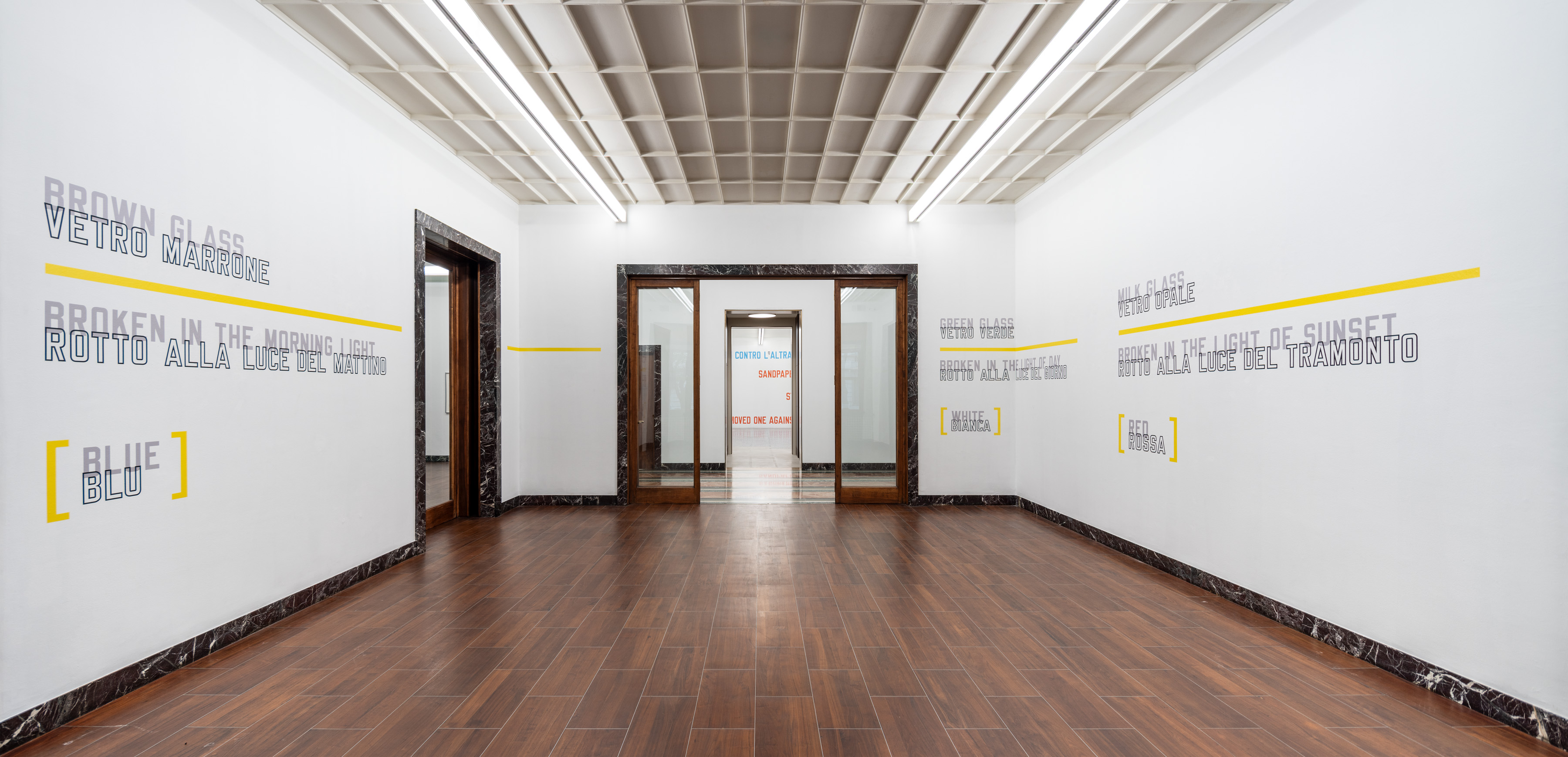 The first room sets the three glass propositions against one another, while yellow holds the same height across walls, openings, and bare intervals. Image Credit: Installation view. Courtesy of the Artist and MASSIMODECARLO. Photo: Roberto Marossi.