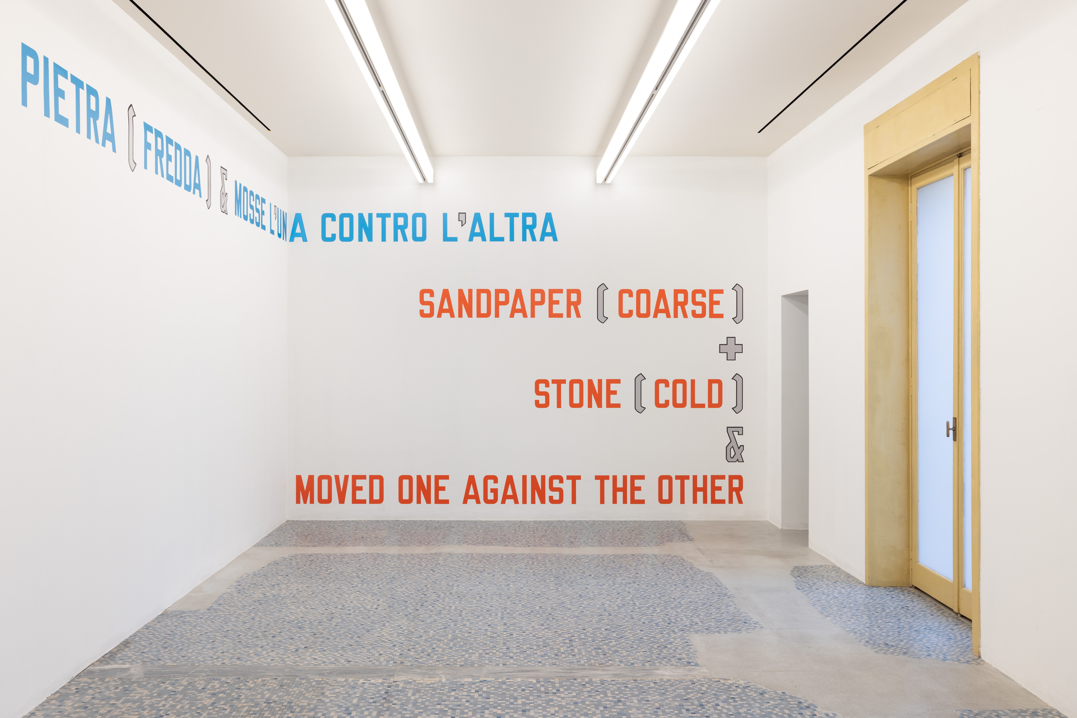 In SANDPAPER, coloured words are accompanied by grey brackets, a plus sign, and an ampersand, making the signs legible as a distinct graphic register. Image Credit: Installation view. Courtesy of the Artist and MASSIMODECARLO. Photo: Roberto Marossi.