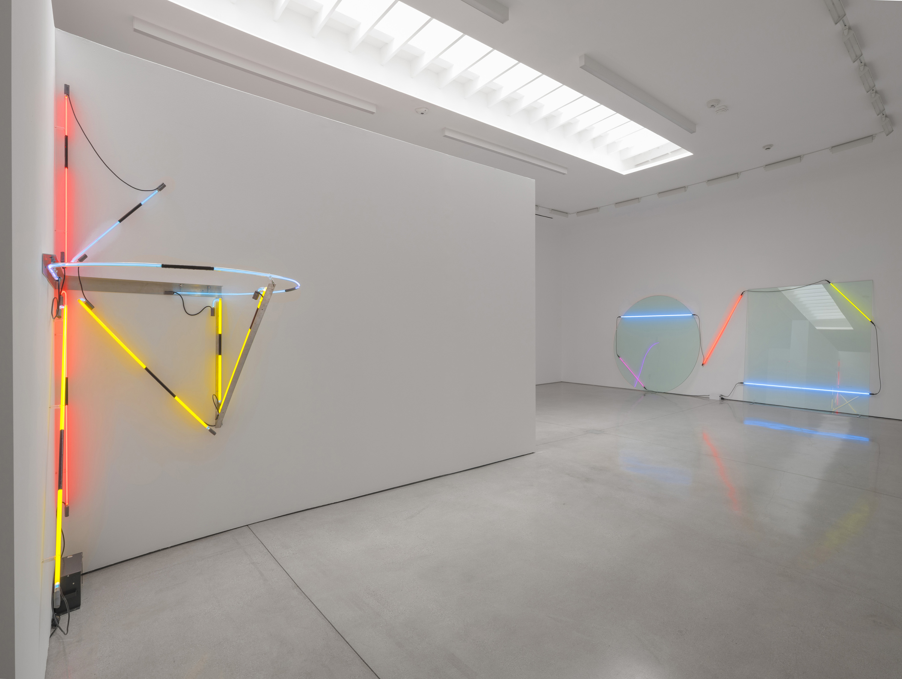 The straight aluminum member bridges the corner instead of following it, and a tube bent into a ring lies flat above it. Image Credit: Installation view. Courtesy Estate of Keith Sonnier and David Kordansky Gallery. Photo: Jeff McLane.