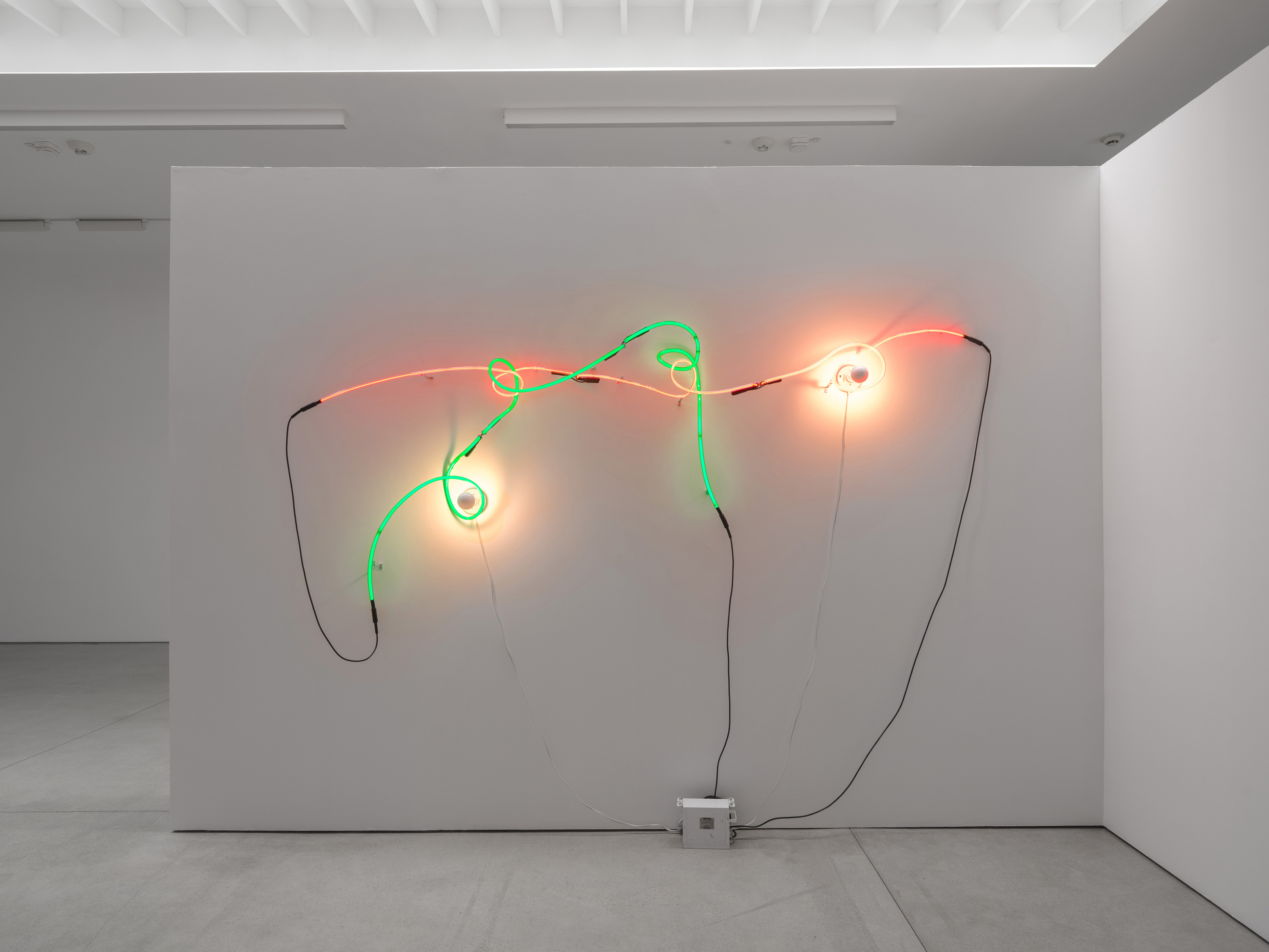Neon Wrapping Incandescent V: two tubes, two porcelain lamps, one galvanized box where black cables and white cords converge. Image Credit: Installation view. Courtesy Estate of Keith Sonnier and David Kordansky Gallery. Photo: Jeff McLane.