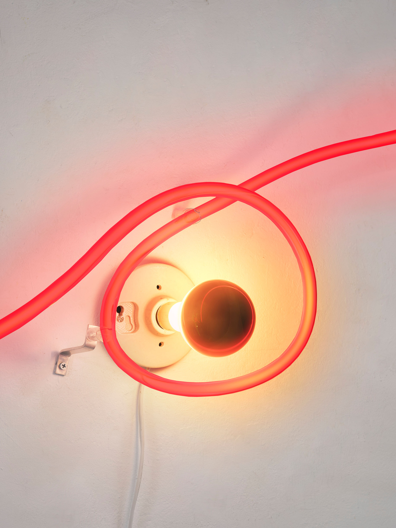 The loop rings the lamp-holder, apparently without touching it. The lamp's own white cord drops away below. Image Credit: Neon Wrapping Incandescent V, 1970 (detail). Courtesy Estate of Keith Sonnier and David Kordansky Gallery. Photo: Jeff McLane.