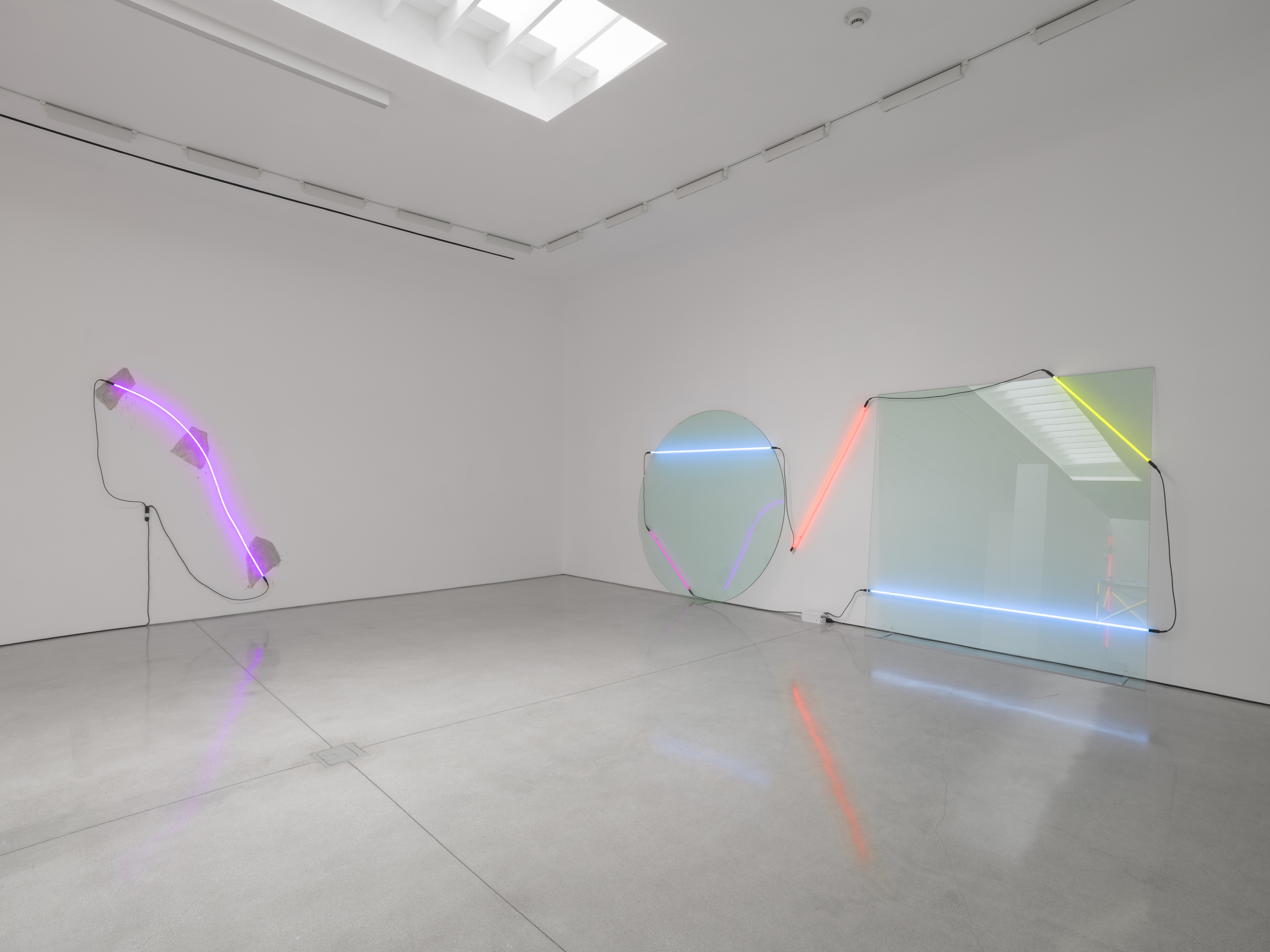 Across the room, Arced Neon (Violet) answers Cool White with the arc reversed: top end and unit at the left, lower end at the right. Image Credit: Installation view. Courtesy Estate of Keith Sonnier and David Kordansky Gallery. Photo: Jeff McLane.