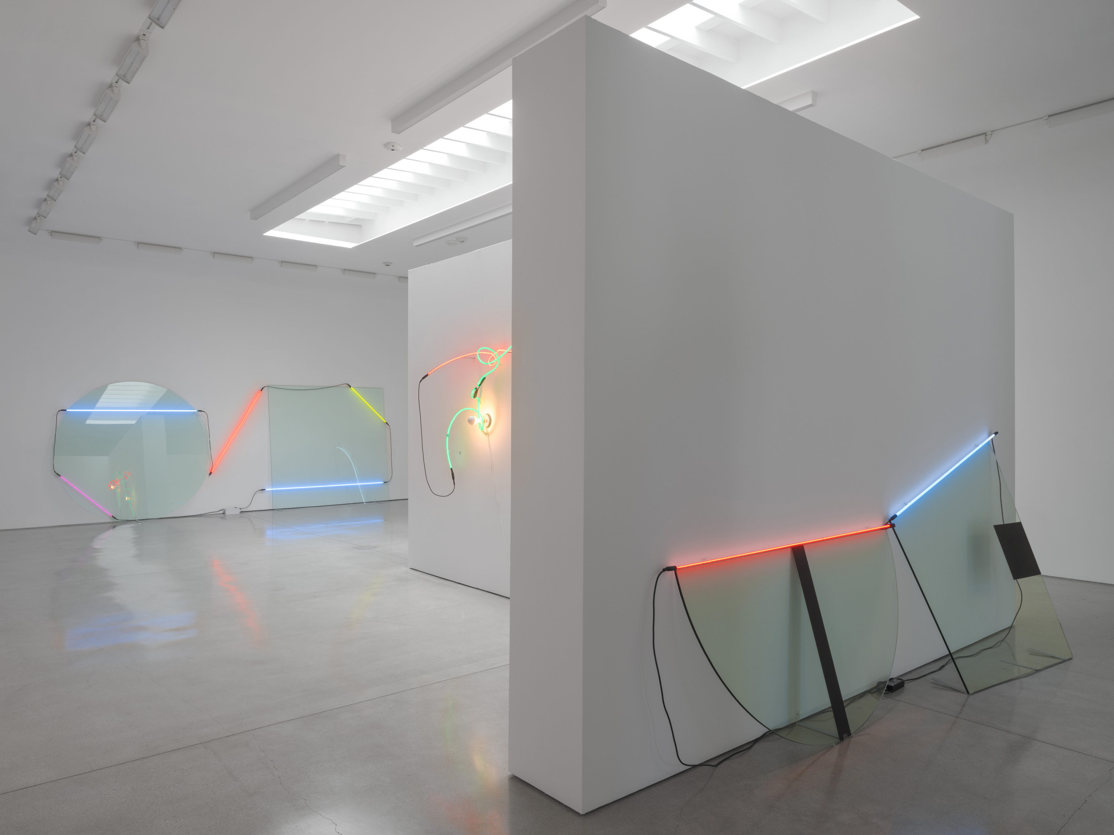 From the partition's west end Dyad Cut returns from its other side, the half-disc nearest, the rest of the room beyond. Image Credit: Installation view. Courtesy Estate of Keith Sonnier and David Kordansky Gallery. Photo: Jeff McLane.