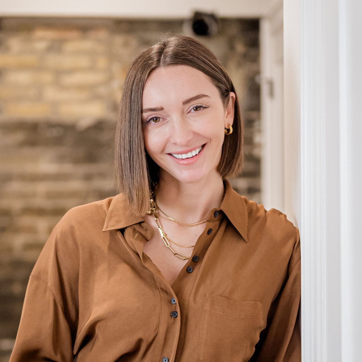 Image of a woman with short brown hair smiling and leaning against a wall.