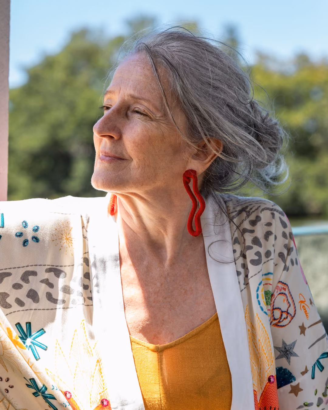 Smiling older woman with grey hair smiling off to the distance.