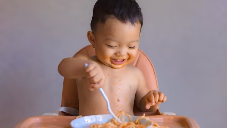 A baby tucking into some baby food