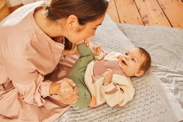 A mother playing with her baby both are smiling