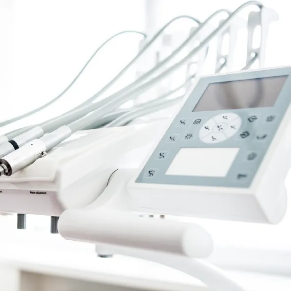 Close-up of a dental equipment control panel and attached handpieces in a bright clinical setting.