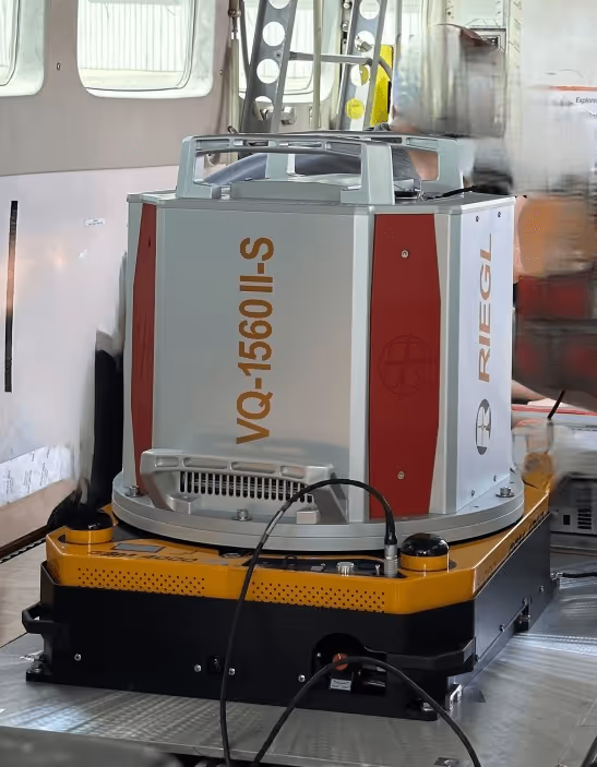 RIEGL VQ-1560 II-S laser scanning device mounted on a yellow and black platform inside an aircraft.