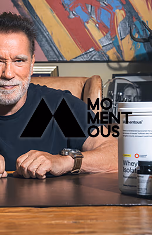 Man with a beard sitting at a table with nutritional supplements and a colorful abstract painting in the background.
