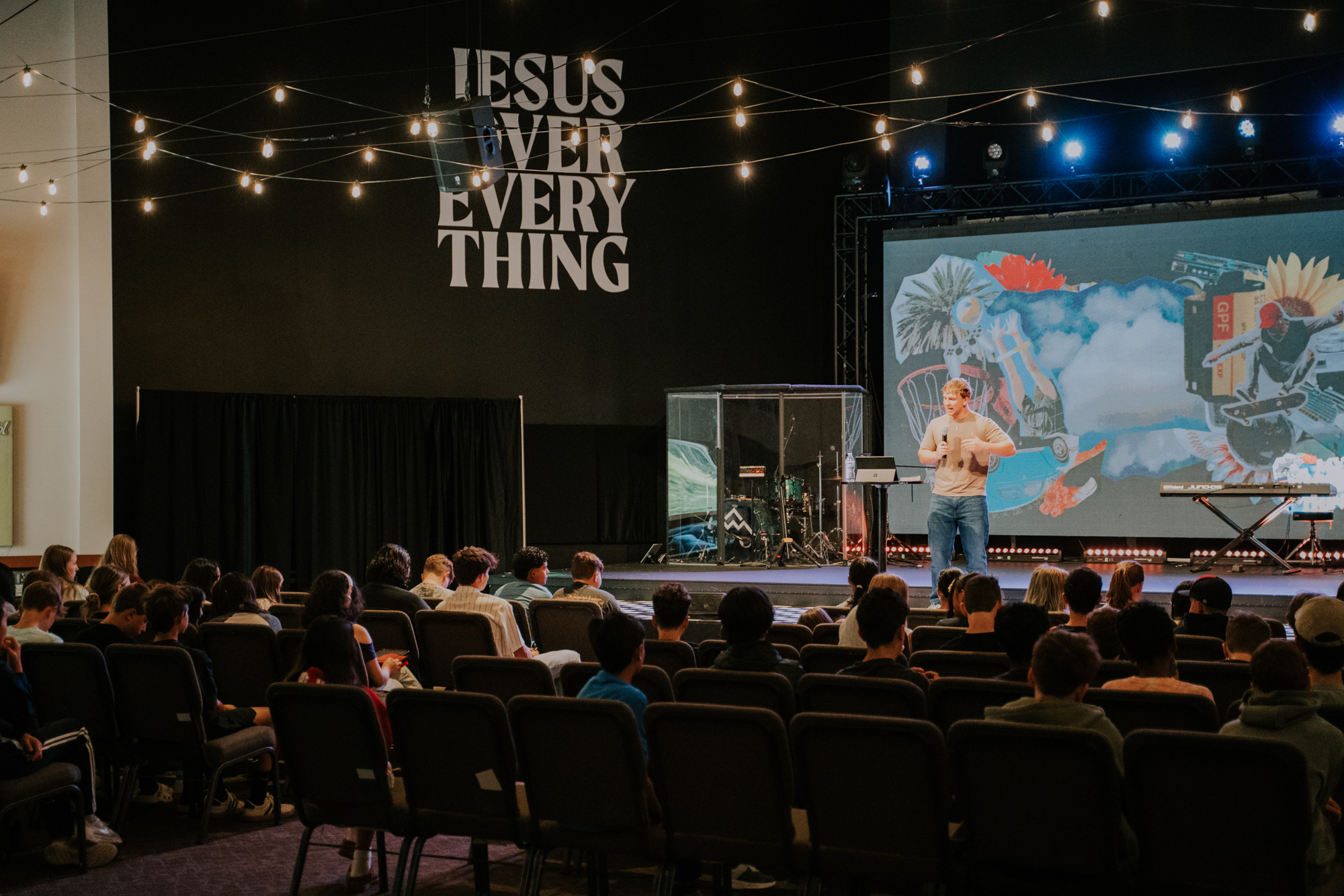 A youth pastor preaching on stage to an audience of high schoolers.