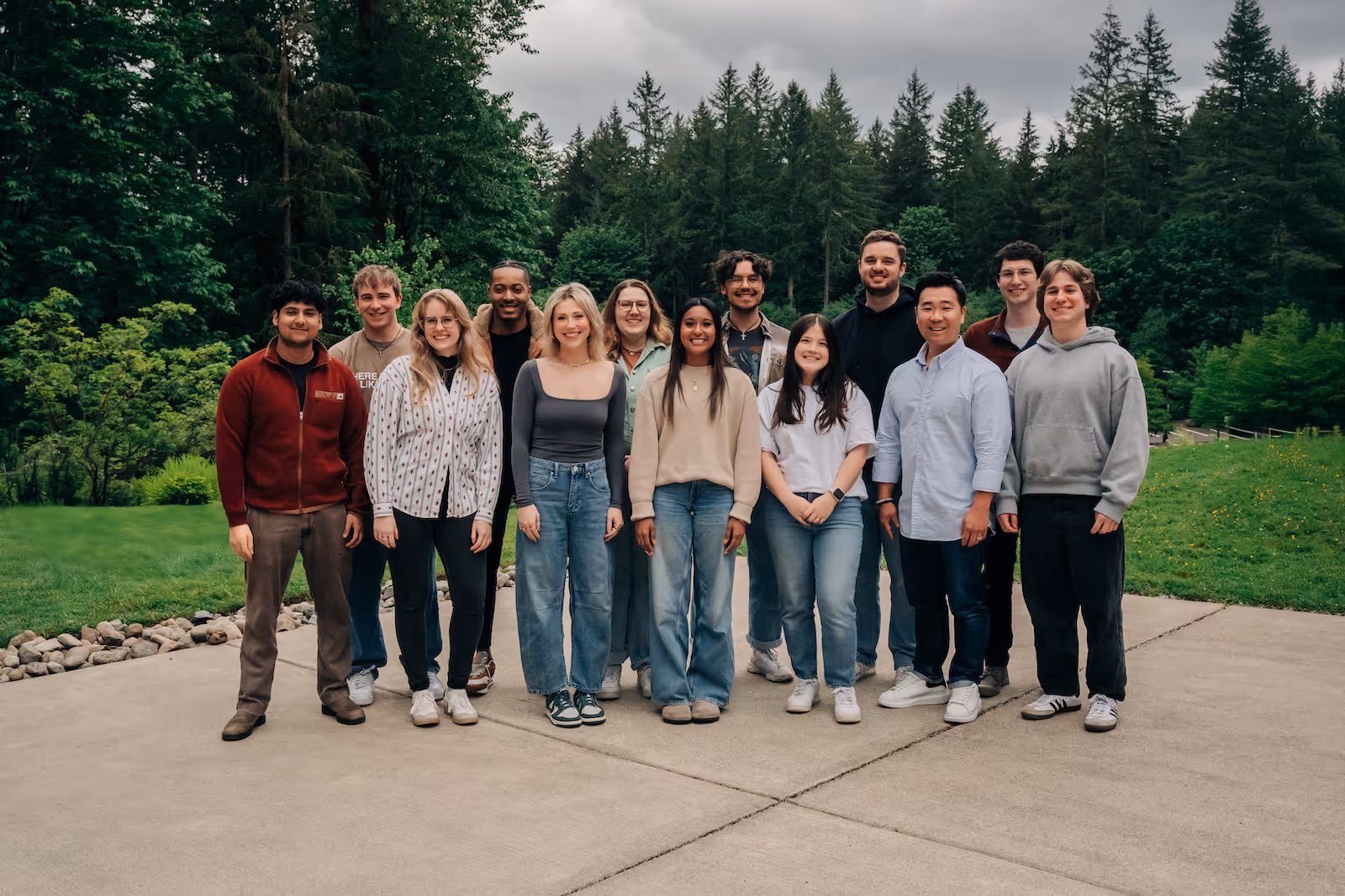 A group of residents outside with Evergreen trees in the background smiling at the camera together.