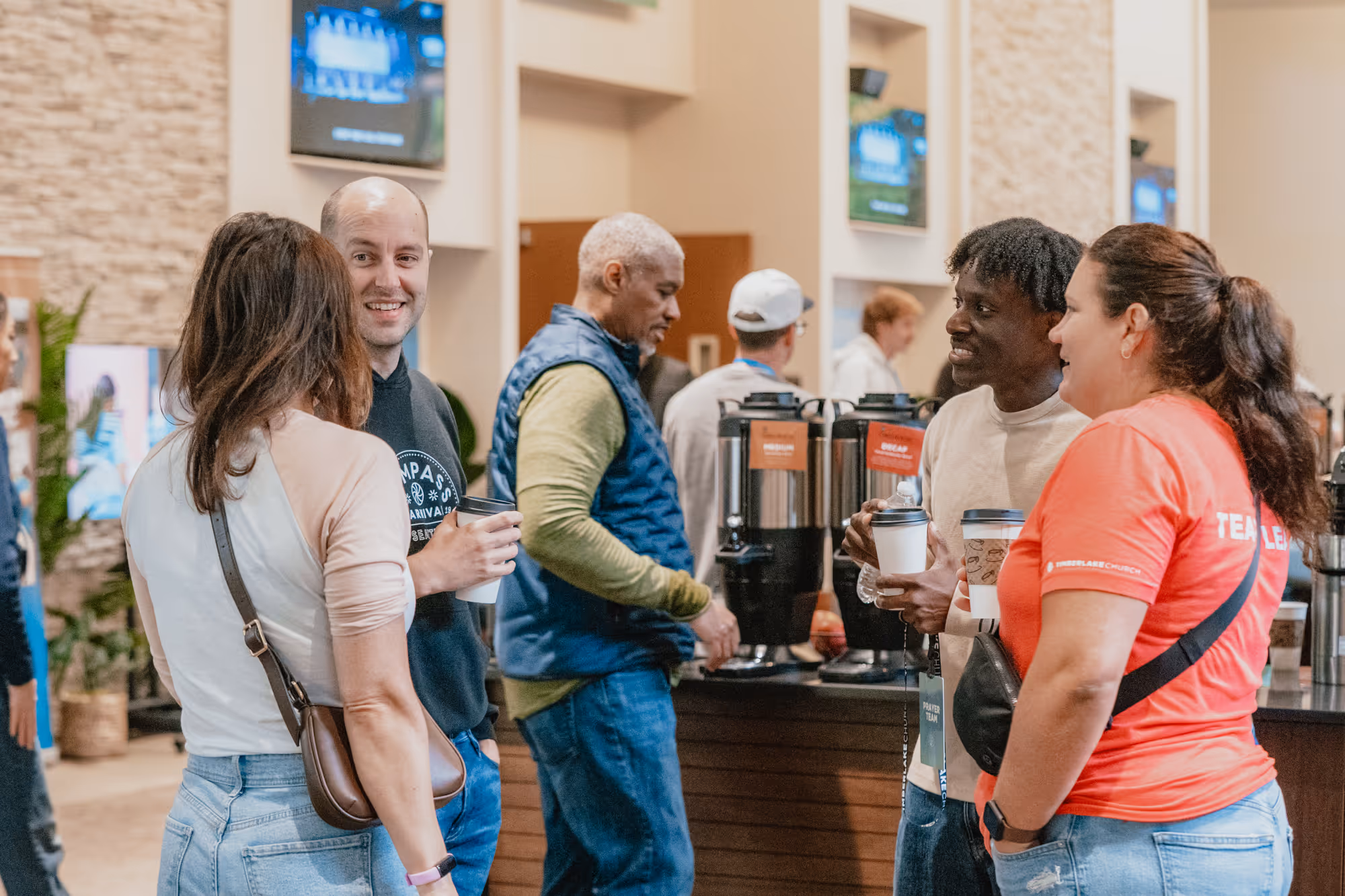 Groups of people standing in the lobby talking to each other.
