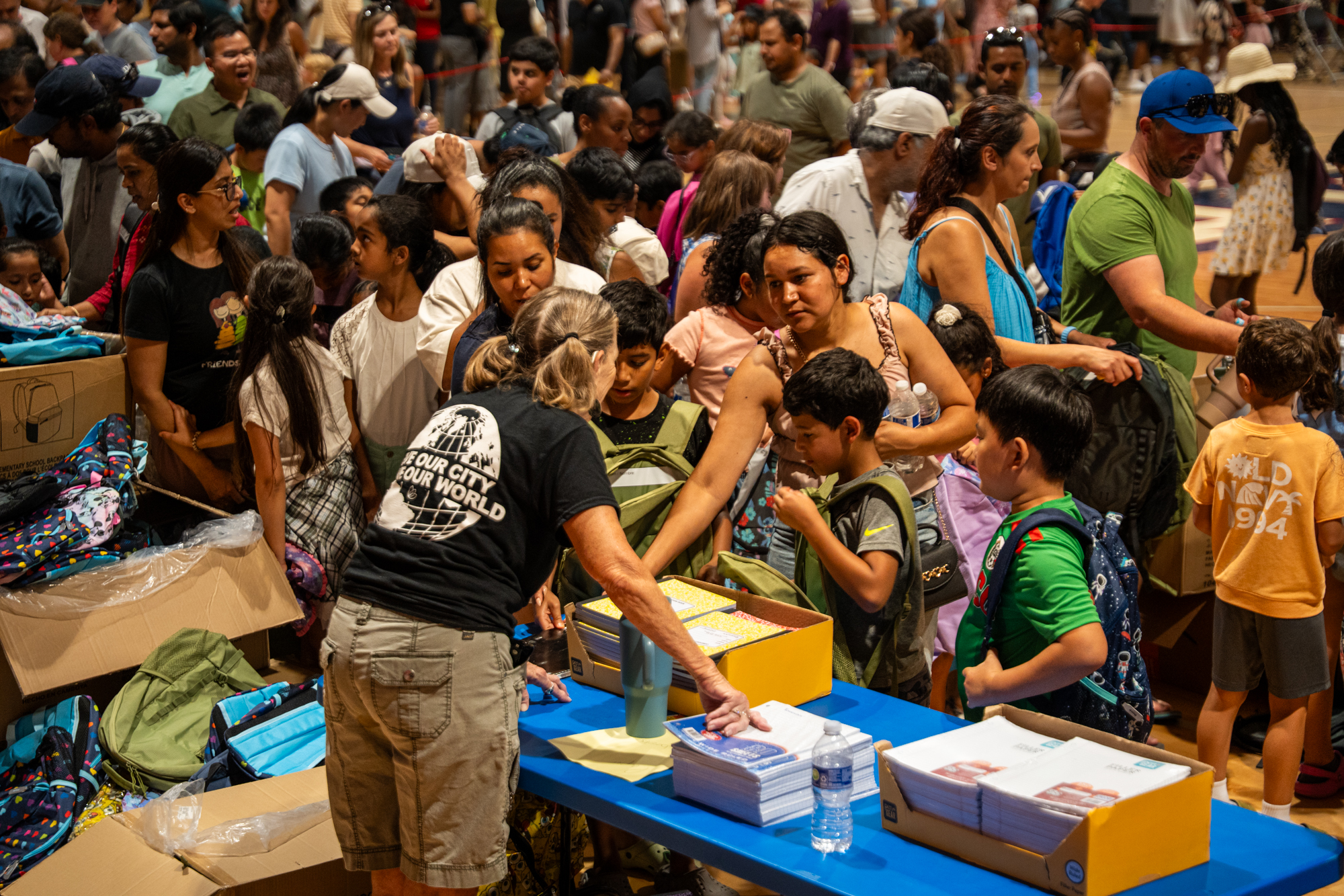 A Timberlake volunteer helping hand out back to school supplies to hundreds of kids in a school auditorium.