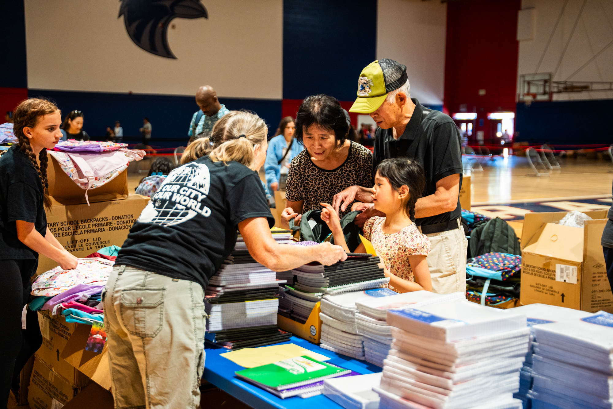 A Timberlake volunteer helping hand out back to school supplies to hundreds of kids in a school auditorium.