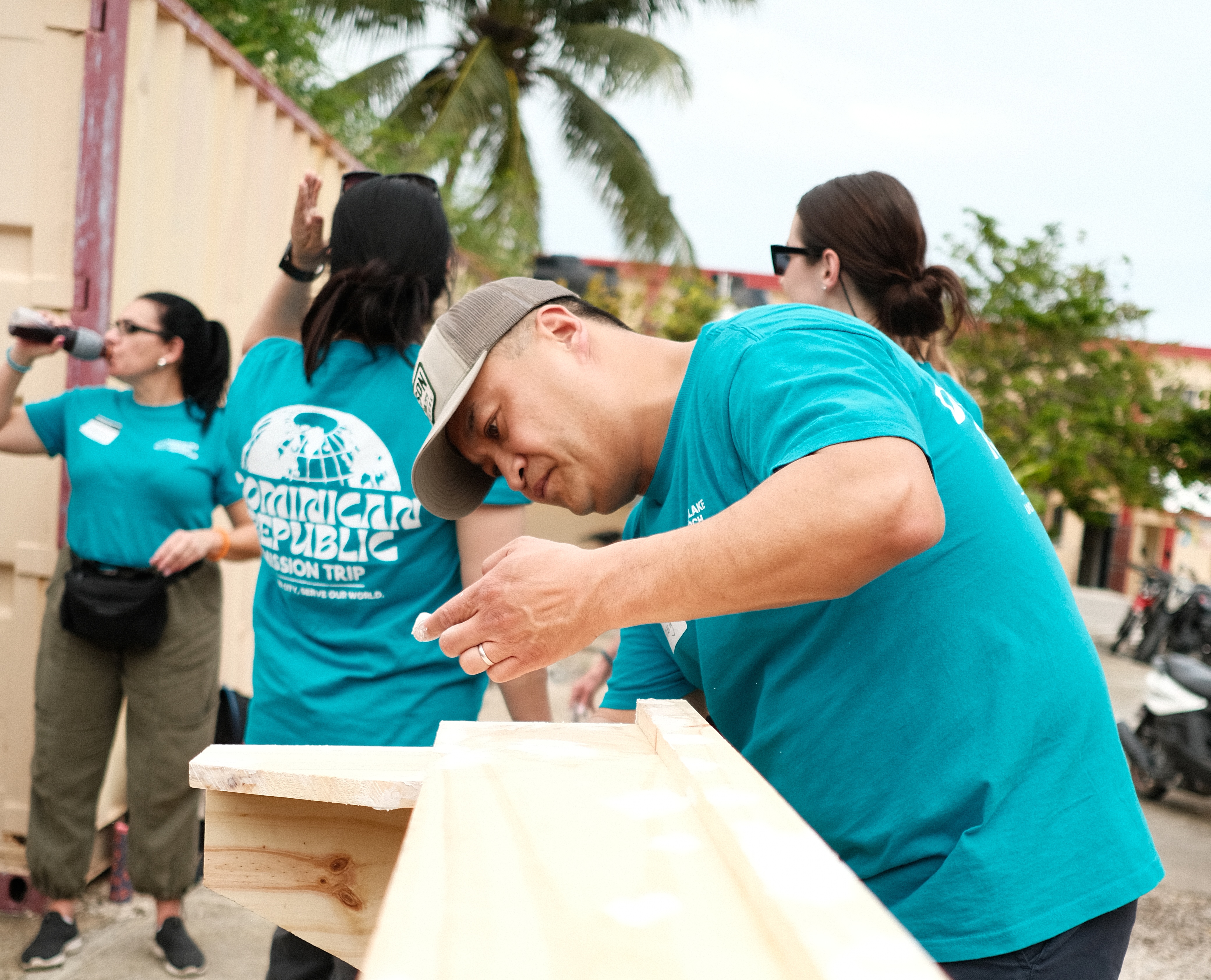 A guy building a wooden structure with a group of volunteers.