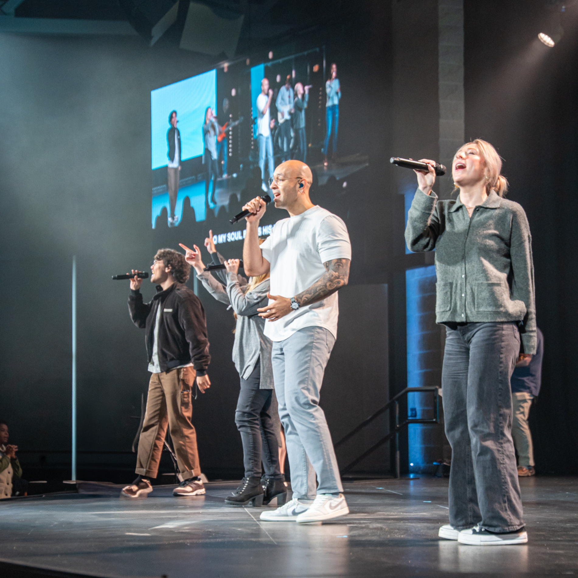 A side view of the stage with the worship team singing together.