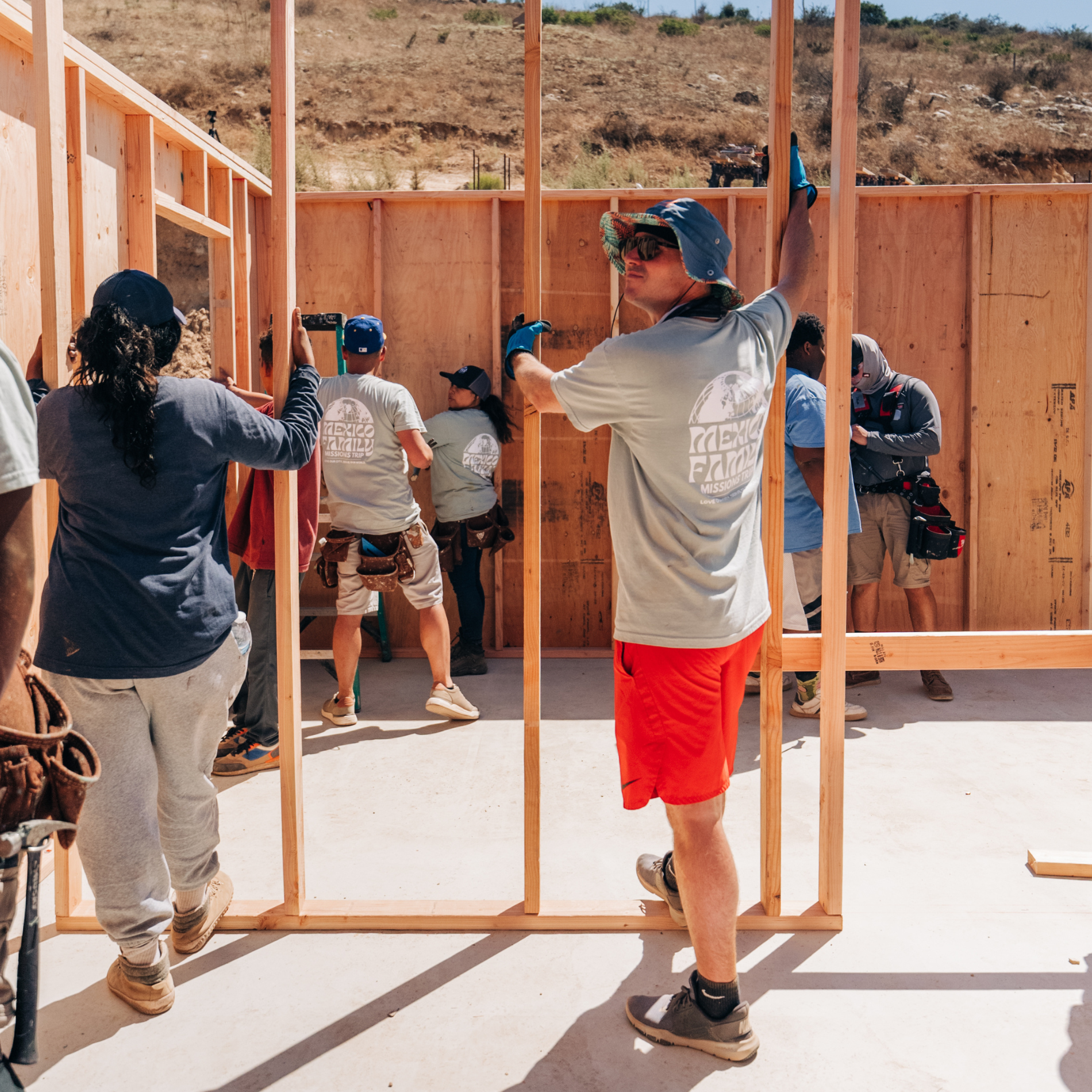 A group of volunteers holding a base of a wooden structure up.