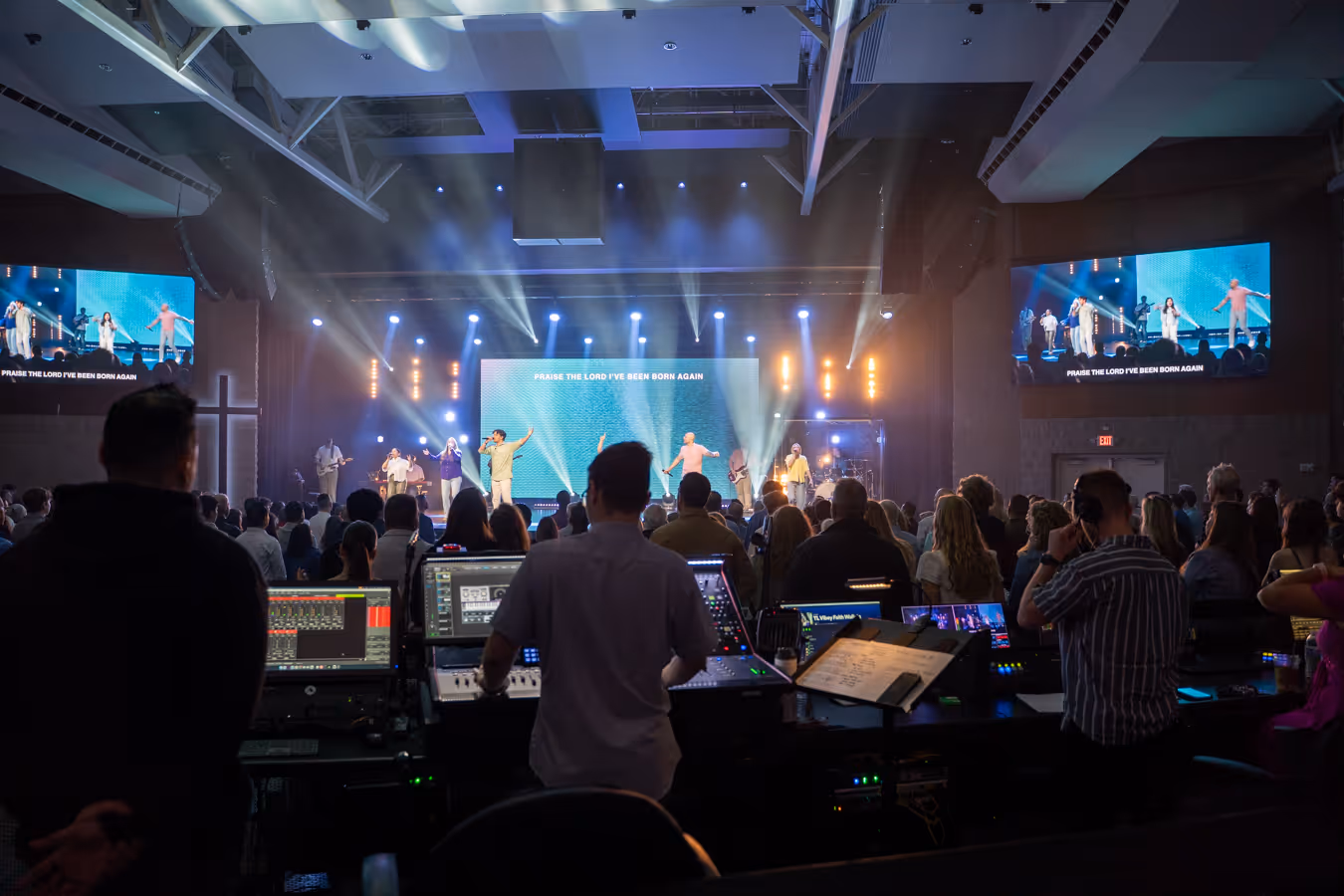 A landscape view from the back of the main auditorium with the audience and the stage of the worship team singing.