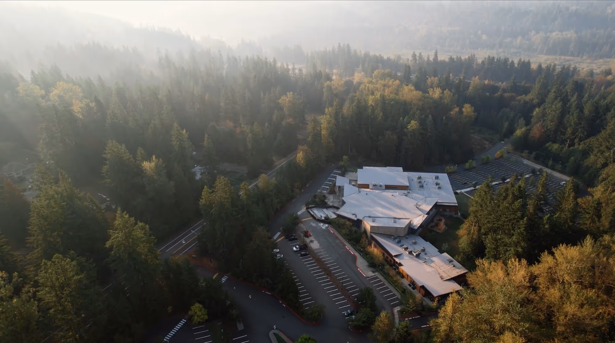 A drone shot of the main campus building surrounded by evergreen trees.