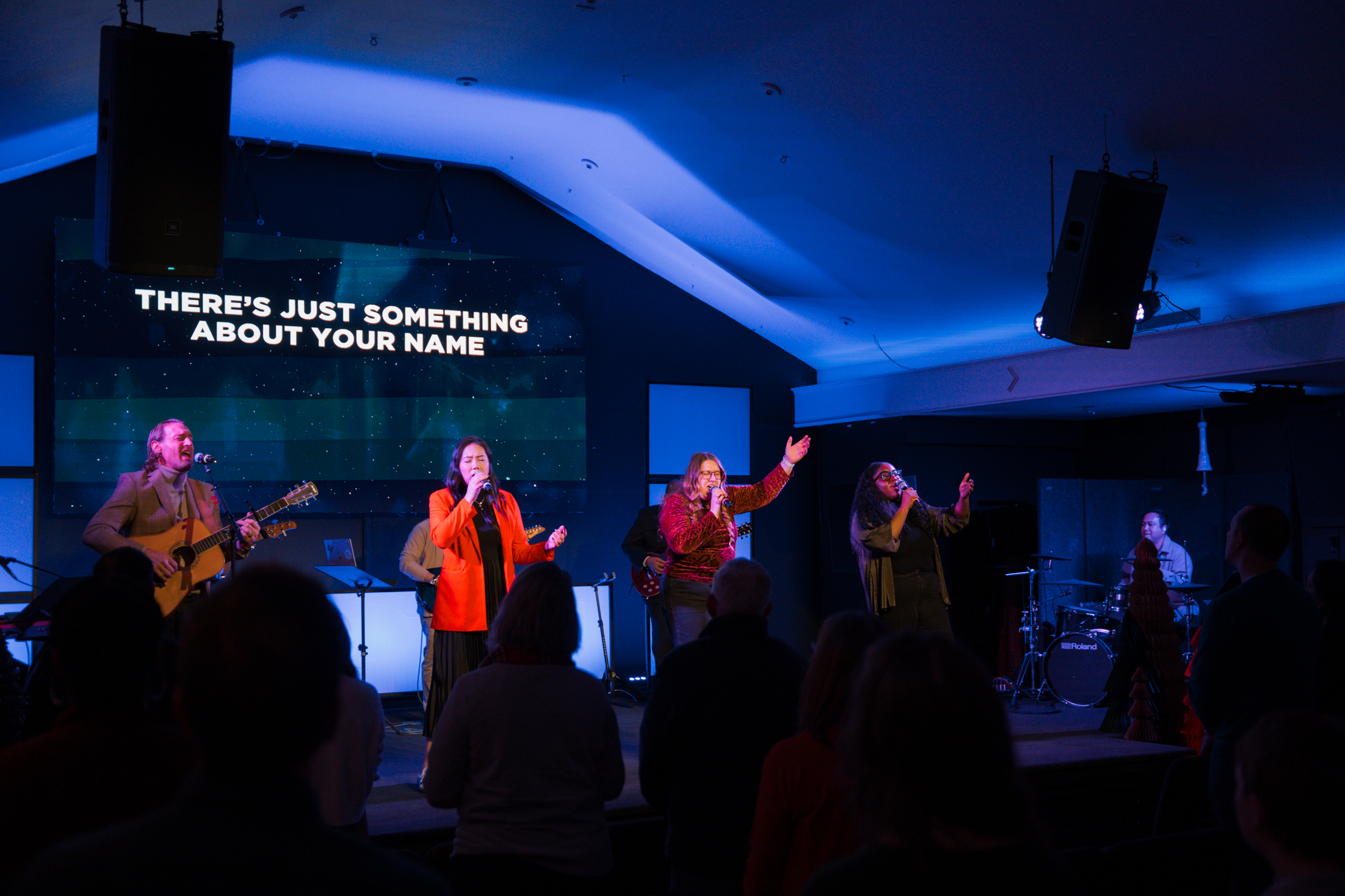 A group of people standing on the stage worshiping together.
