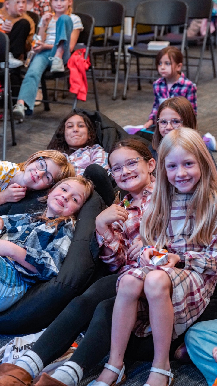 Group of smiling girls sitting and lying on bean bags in a casual indoor setting.
