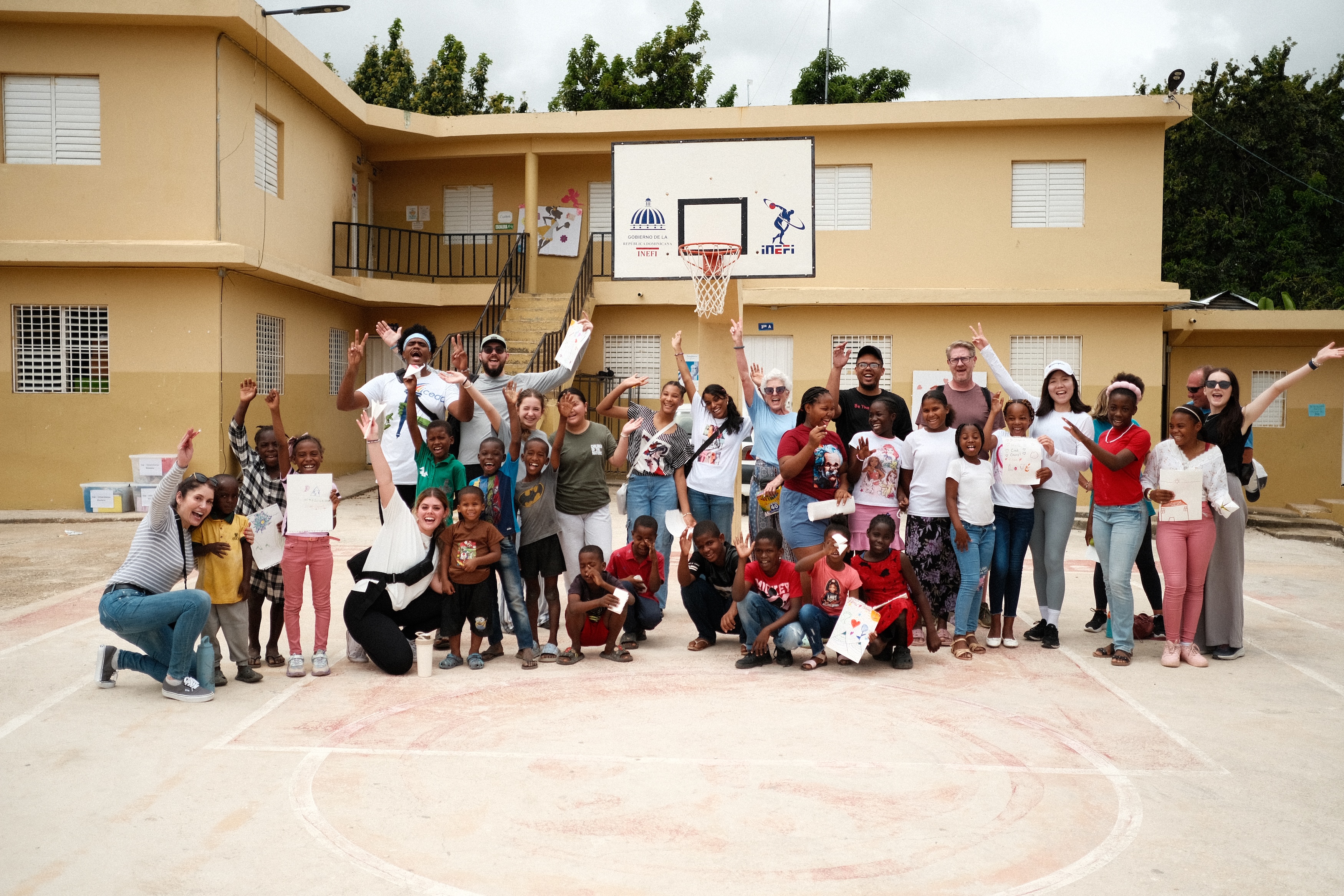 A large group of children and adults in front of a school for a picture.