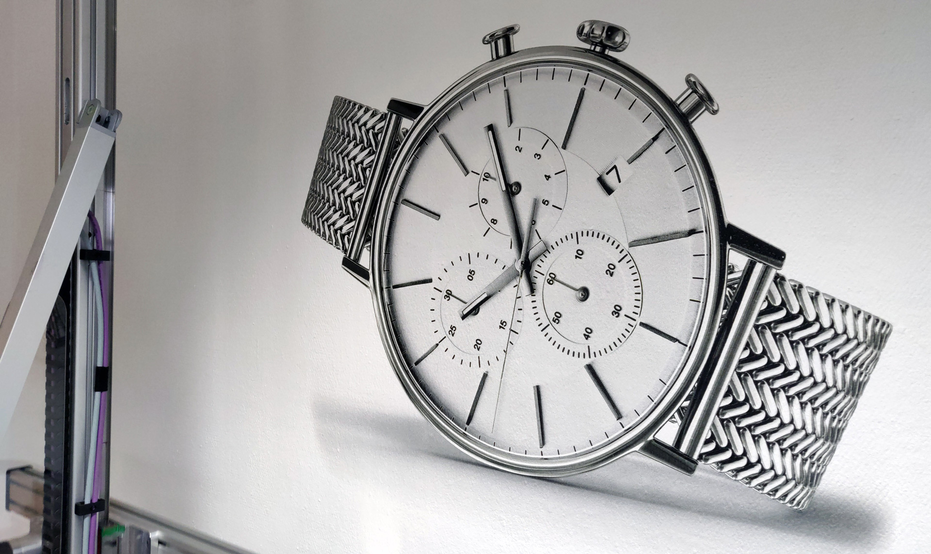 Silver wristwatch with a mesh band and three subdials showing time and a date window displaying the number 7.