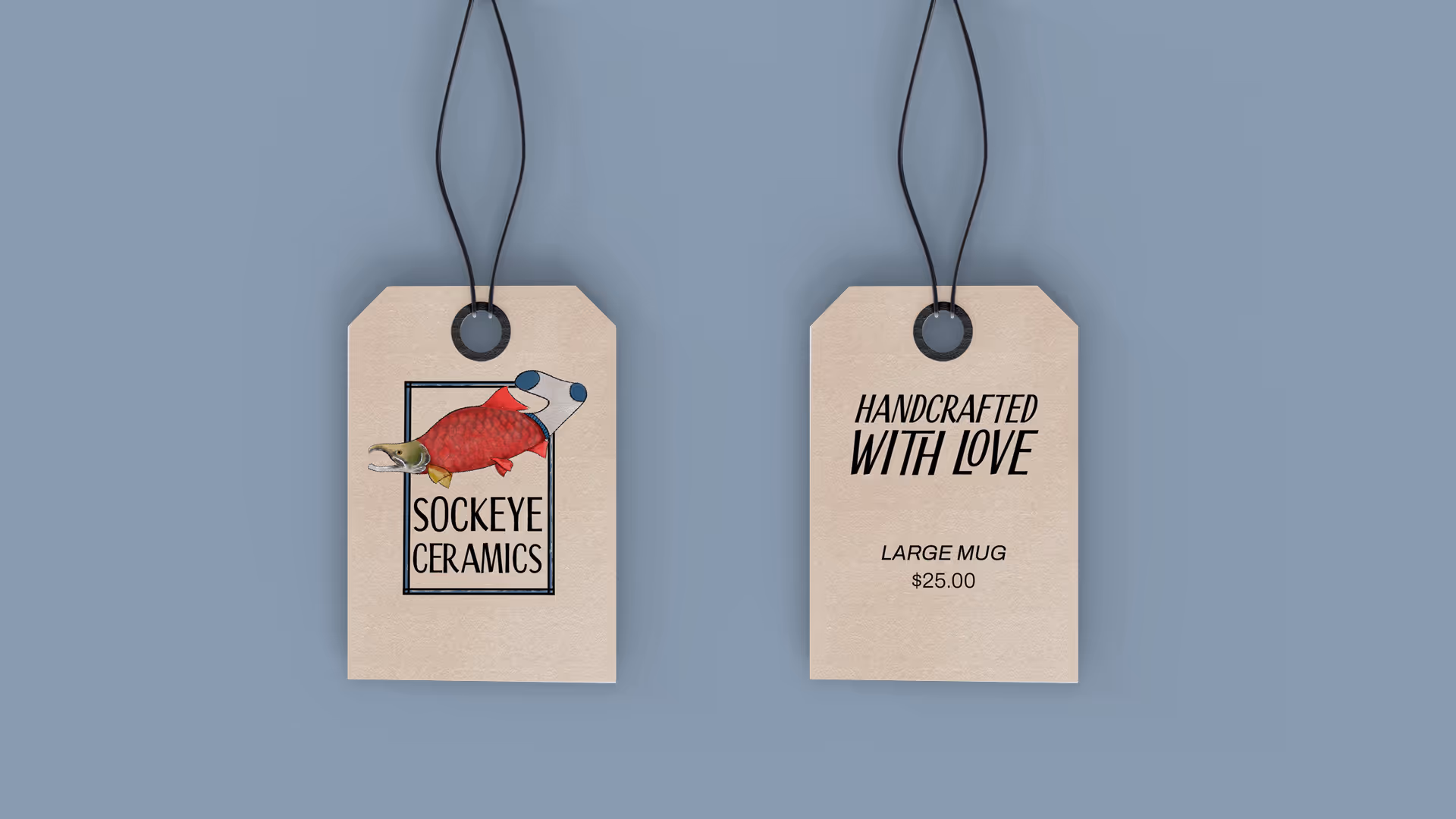 Two beige hanging product tags on a gray background; left tag shows a red fish illustration and 'Sockeye Ceramics' text, right tag reads 'Handcrafted With Love', 'Large Mug', and '$25.00'.