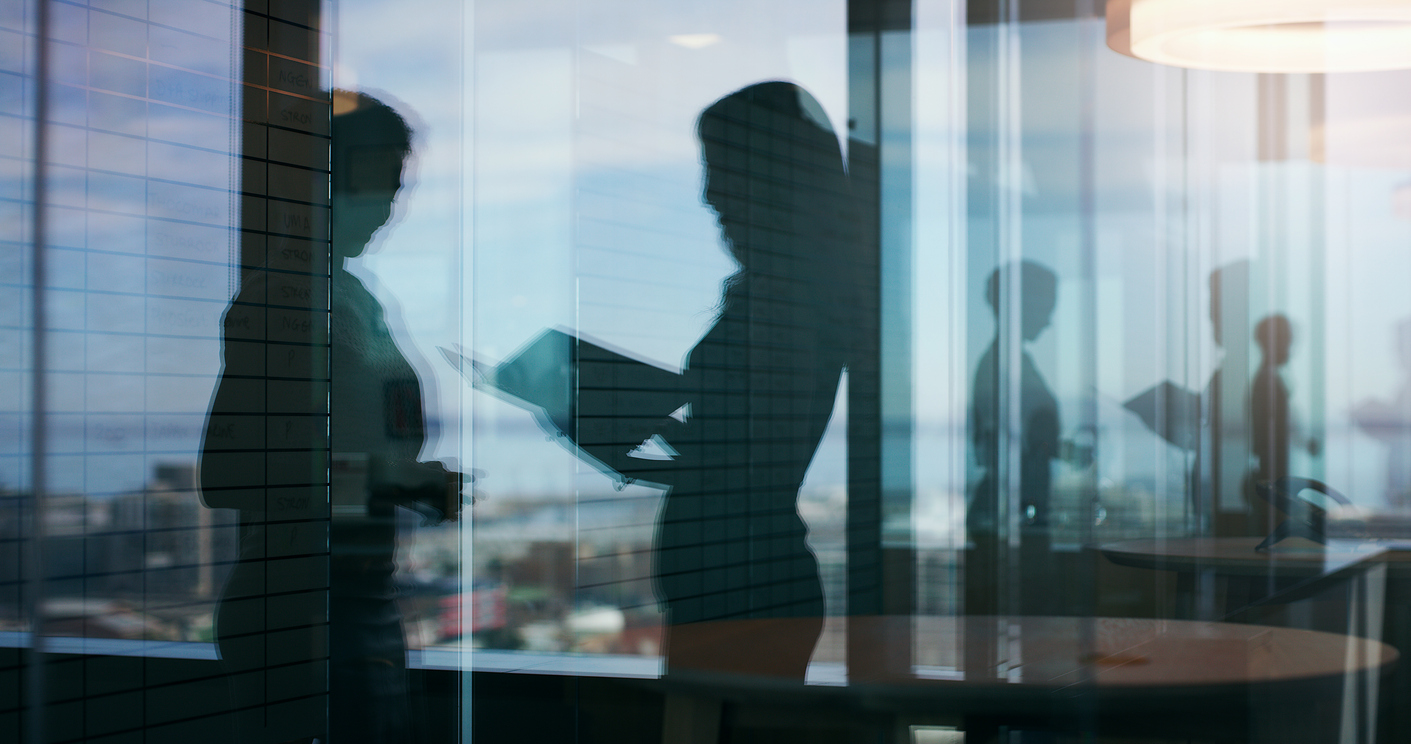Two women shown talking in an office setting through a series of reflections in glass.