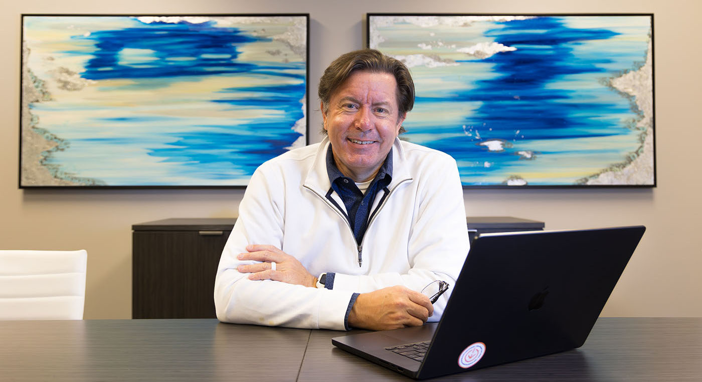 A mature professional seated in front of his computer in a conference room.